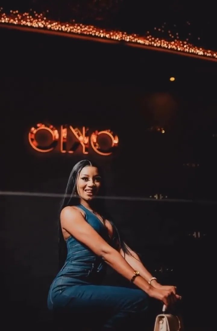 Guest seated at the bar beneath the neon OKIO sign